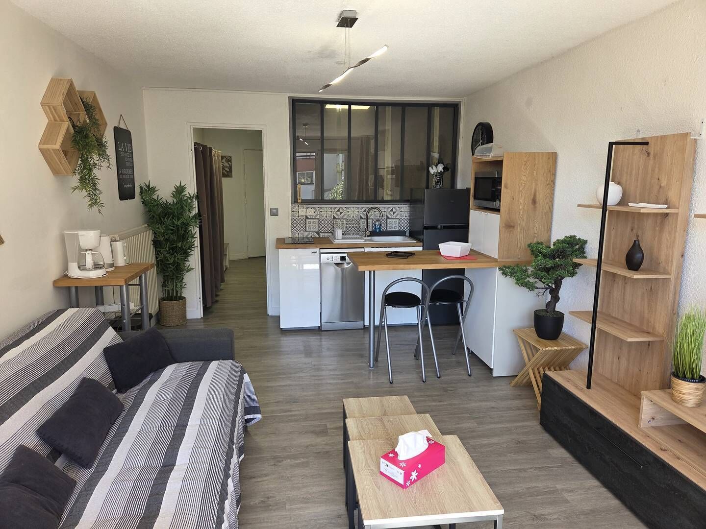 A modern living room with a sofa, a coffee table, and a kitchen in the background.