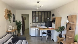Un salon moderne avec un canapé, une table basse et une cuisine en arrière-plan.