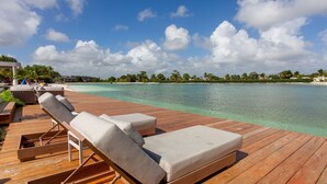 A wooden deck with lounge chairs and a view of a clear turquoise sea and palm trees. - 2 Bedrooms with Pool View (Punta Cana)