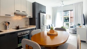 A modern kitchen with a built-in oven, a refrigerator, and a dining area with a round table and chairs. - 2 Bedrooms with Pool View (Punta Cana)