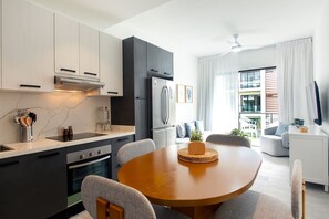 A modern kitchen with a built-in oven, a refrigerator, and a dining area with a round table and chairs. - 2 Bedrooms with Pool View (Punta Cana)