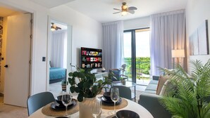 Ett modernt hotellrum med en matplats, en balkong med utsikt, en takfläkt och en bokhylla.