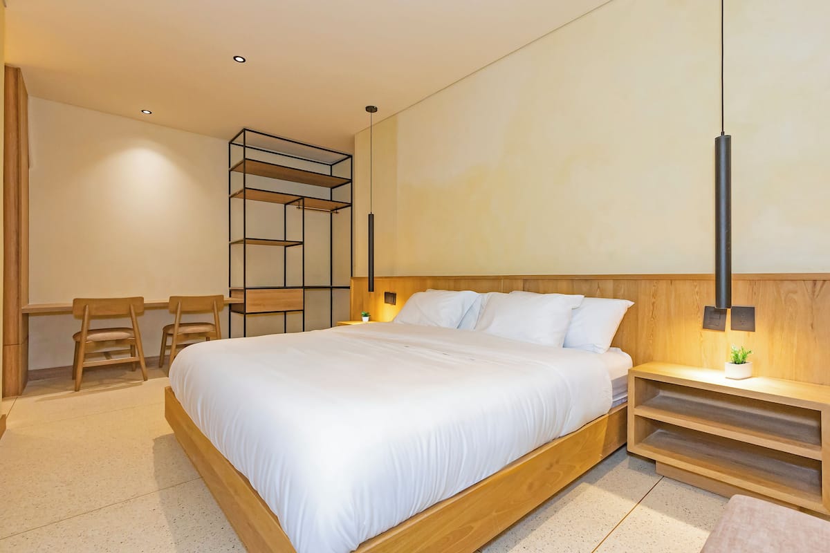 Una camera da letto moderna con un letto di legno, una scrivania con sedie e scaffalature integrate.