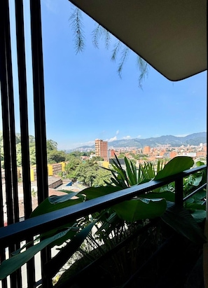 A balcony with a view of a cityscape, including buildings and mountains. - Hotel Iconik (Medellín)