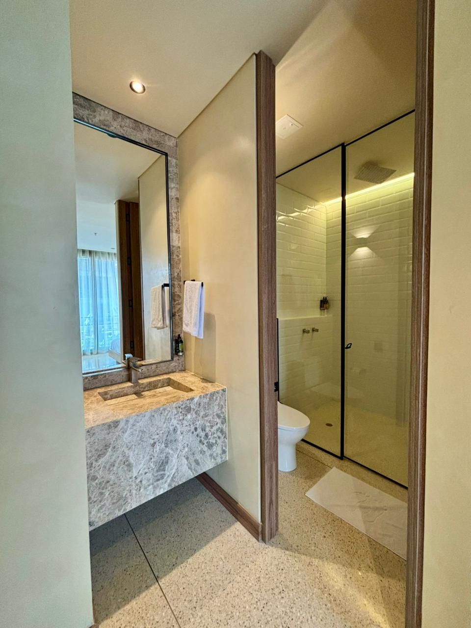 A modern bathroom with a marble sink, a glass-enclosed shower, and a large mirror.