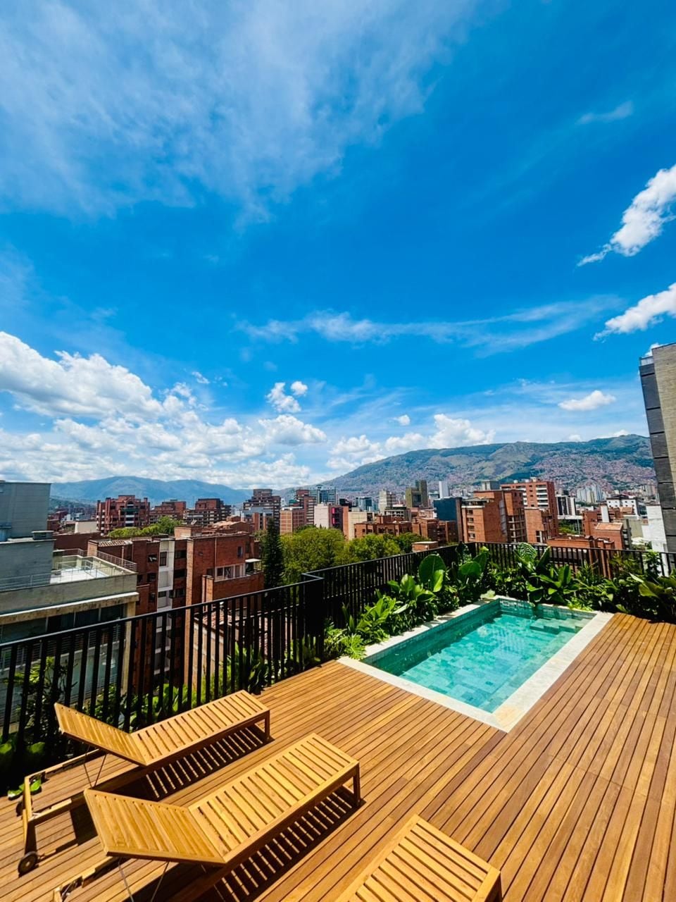 A rooftop terrace with a swimming pool, lounge chairs, and a cityscape view.