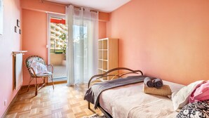 A bedroom with a bed, a chair, a radiator, and a view of the outside. - Apartment "Accommodation for 4 People" with Private Terrace and Wi-Fi (Nice)