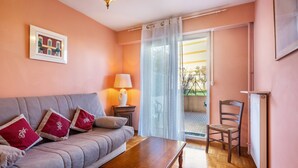 A room with a sofa, a wooden coffee table, a chair, a lamp, and a window with a view. - Apartment "Accommodation for 4 People" with Private Terrace and Wi-Fi (Nice)