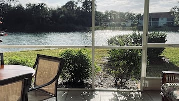 Un patio con vistas a un lago, una mesa y sillas.