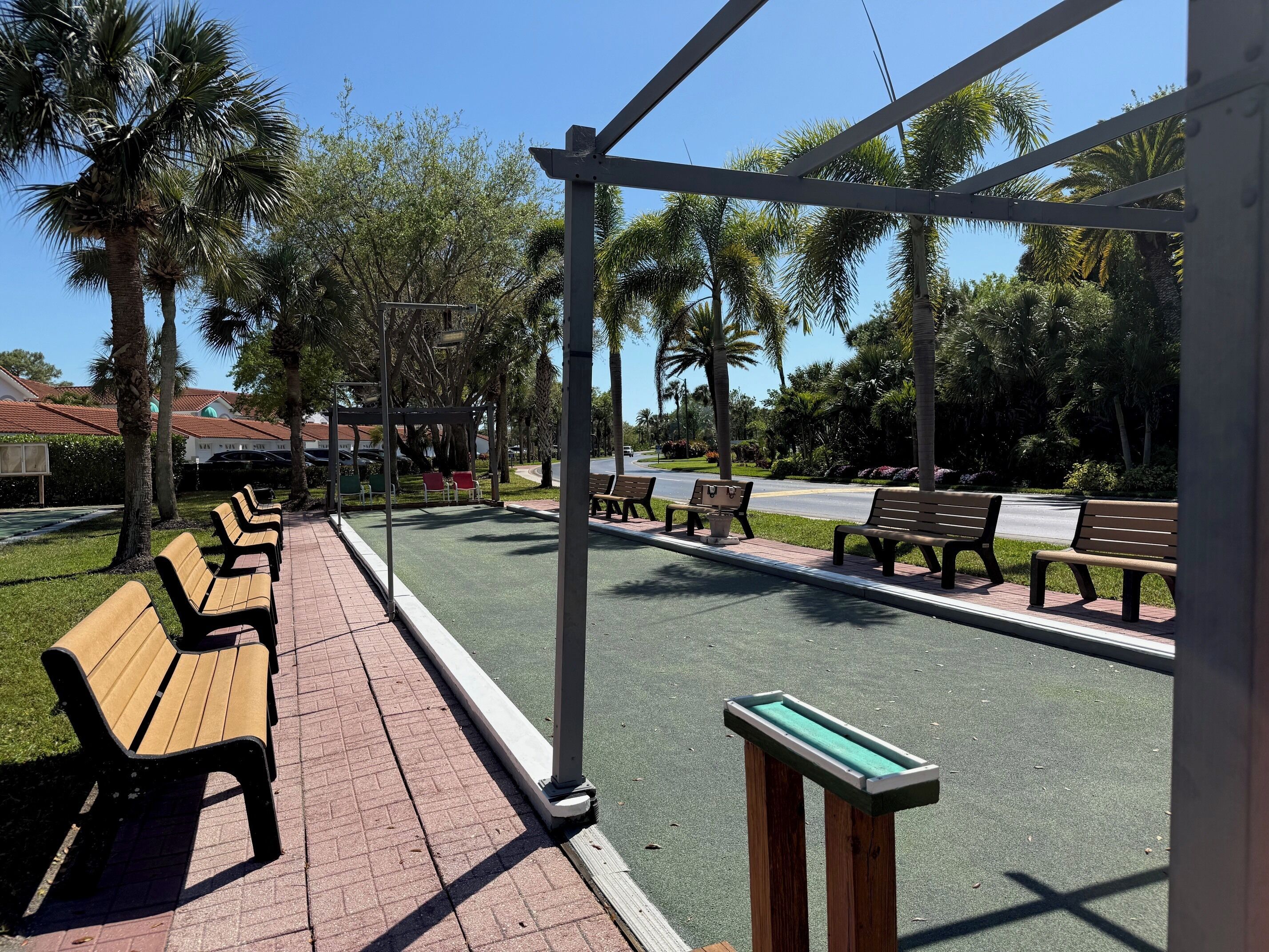 Un parque con bancos, un área de juegos y una calle.