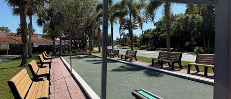 A park with benches, a playground, and a street.