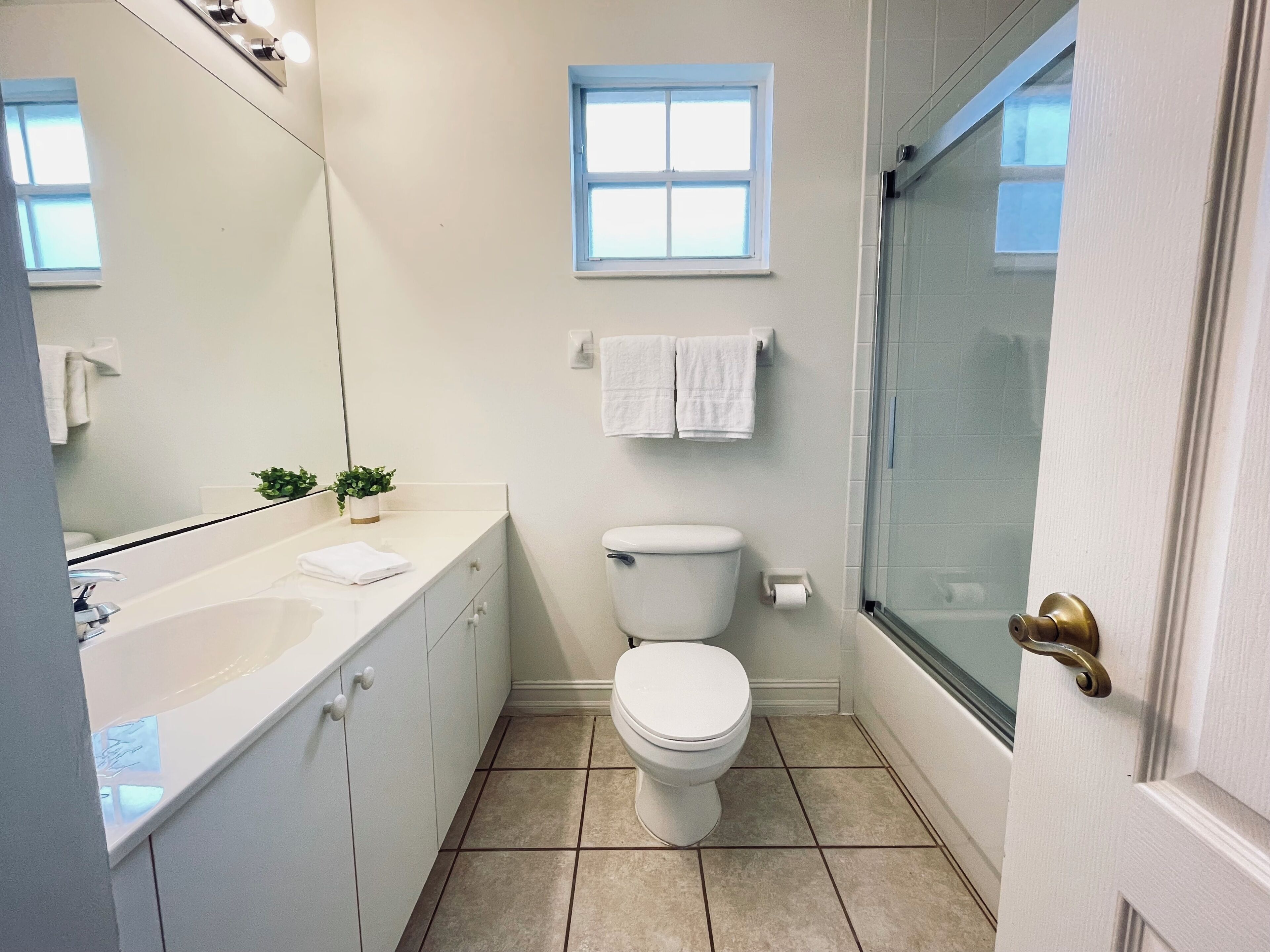 A compact bathroom with a white sink, toilet, and shower area.