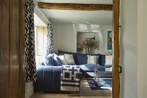 A living room with a blue sofa, patterned throw, and a wooden floor. - Perfect for large groups. Be it birthdays, wedding parties or a family and friends get-together, we (Bibury)