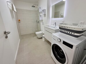 Ein modernes Badezimmer mit Dusche, Toilette, Waschbecken und Waschmaschine.