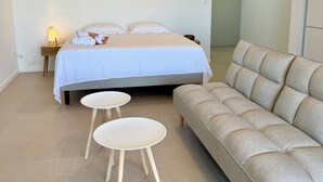 A bedroom with a bed, two round tables, and a sofa. - Studio Vairagi City, brand new in the center of Papeete, WiFi -Netflix -A/C (Papeete)