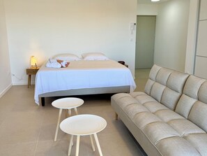 Ein Schlafzimmer mit einem Bett, zwei runden Tischen und einem Sofa.