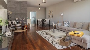 Een moderne woonkamer met een bank, salontafel en een eethoek met stoelen.