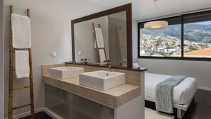 Een moderne badkamer met twee wastafels, een grote spiegel en uitzicht op een stad door een raam.