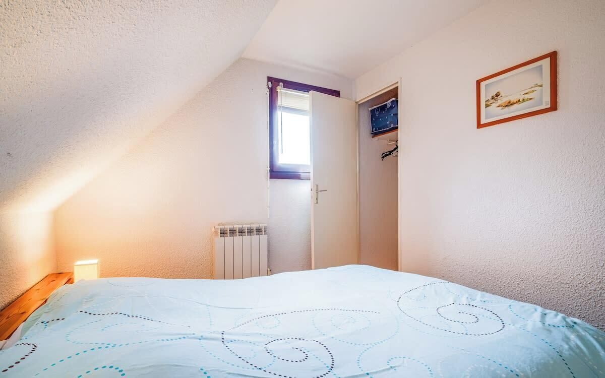 Une chambre à coucher avec un lit, un radiateur, une fenêtre et une porte.