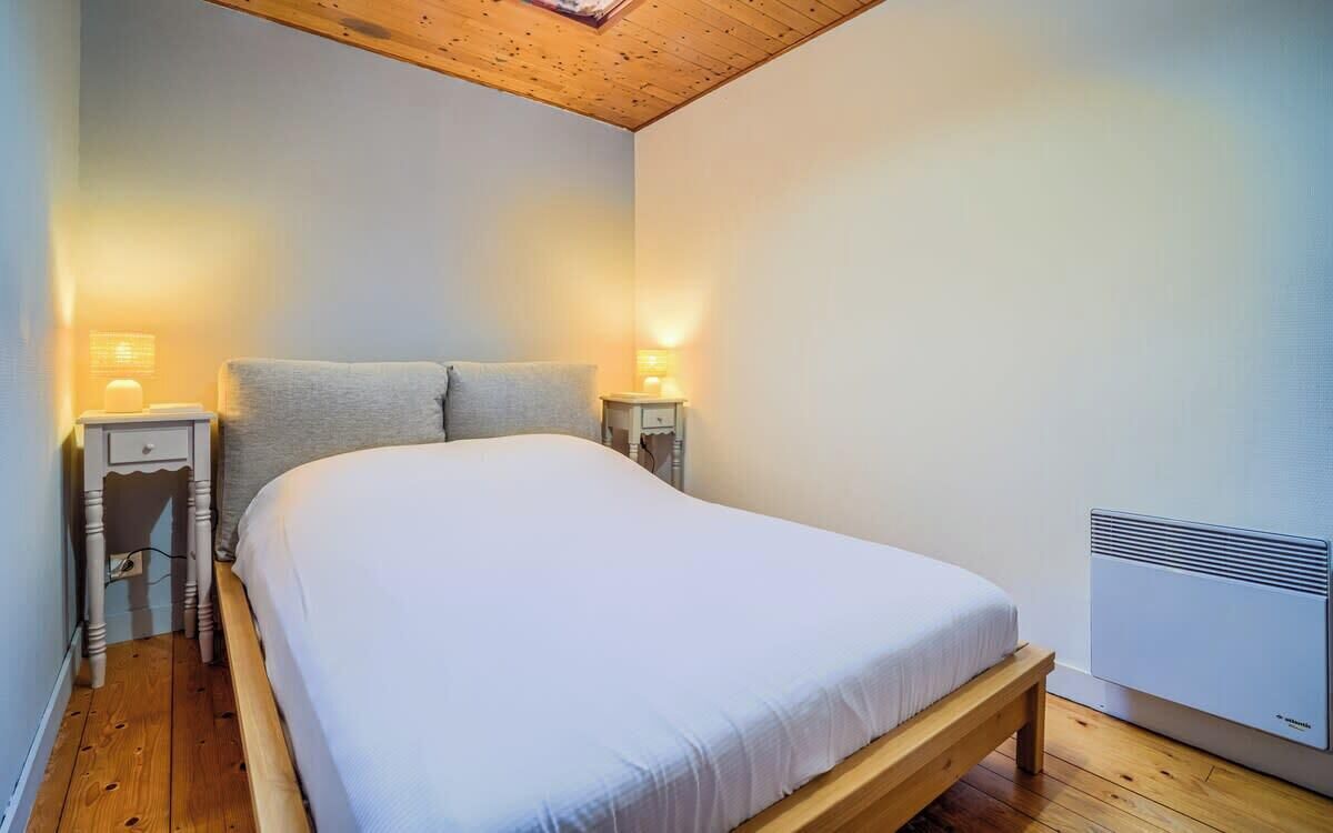 Ein Schlafzimmer mit einem hölzernen Bett, zwei Nachttischen mit Lampen, einem Deckenventilator und einem an der Wand montierten Heizkörper.