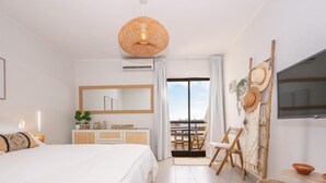 Ein modernes Schlafzimmer mit einem großen Bett, einem Schminktisch, einem Fernseher und einem Balkon mit Gartenmöbeln.