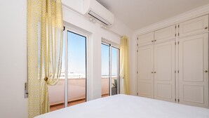 A bedroom with a large bed, sliding glass doors to a balcony, and a wardrobe. - Tavira Getaway with Balcony and Sea View (Tavira)