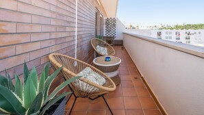 A balcony with two wicker chairs, a small table, and a potted plant. - Tavira Getaway with Balcony and Sea View (Tavira)