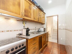 Une cuisine avec des meubles de rangement en bois, une cuisinière à gaz, une machine à café et un grille-pain.
