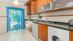 Una cocina moderna con armarios de madera, lavavajillas integrado y lavadora.