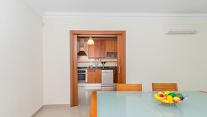 Una cocina moderna con armarios de madera, electrodomésticos de acero inoxidable y una mesa de comedor de vidrio con un frutero.
