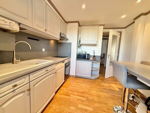A modern kitchen with white cabinetry, a stainless steel sink, and a built-in microwave.
