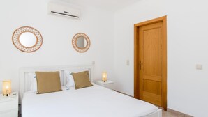 A bedroom with a bed, two bedside lamps, a wooden door, and two wall-mounted mirrors. - Casa do Lagar - 4 mins walk to train station - quiet - wi-fi (Conceição de Tavira)