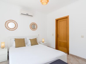 Une chambre à coucher avec un lit, deux lampes de chevet, une porte en bois et deux miroirs fixés au mur.