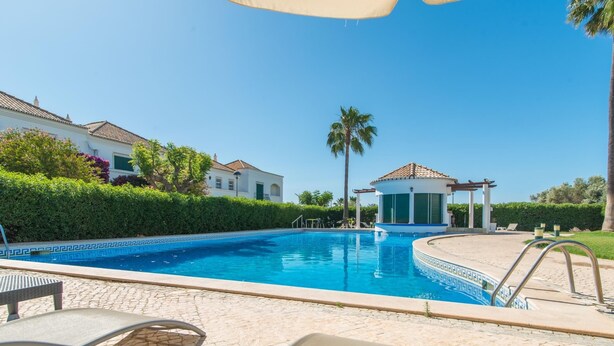 A swimming pool with lounge chairs, a gazebo, and a building in the background. - Casa Oceanus - Magnificent Apartment with Pool (Cabanas de Tavira)