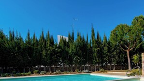 A swimming pool with a stone wall and trees in the background. - Santa Luzia Mar 2BDR | Pool | Wi-Fi | BBQ (Santa Luzia Tavira)