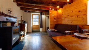 A cozy cabin interior with a wooden floor, a sofa, a dining table, and a fireplace. - LE LEROT - JARSY - Gîte (JARSY)
