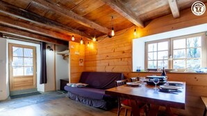A wooden cabin interior with a dining table set for two, a sofa, and a window with a view of the outdoors. - LE LEROT - JARSY - Gîte (JARSY)