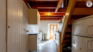 A narrow kitchen with white cabinets, a white refrigerator, and a wooden staircase. - LE LEROT - JARSY - Gîte (JARSY)