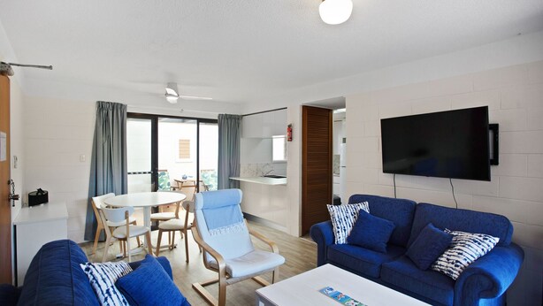 Una sala de estar moderna con un sofá azul, una mesa de centro blanca y un comedor con una mesa y sillas.