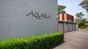 Un edificio con una pared de ladrillo gris y el nombre "AQABA" en letras grandes.