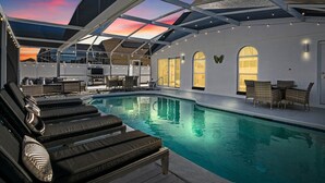 Un espace piscine comprenant des chaises longues, une table et un coin salon abrité.