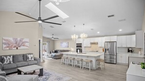 Une cuisine moderne avec des meubles blancs, des appareils en acier inoxydable et un îlot central doté de tabourets de bar.