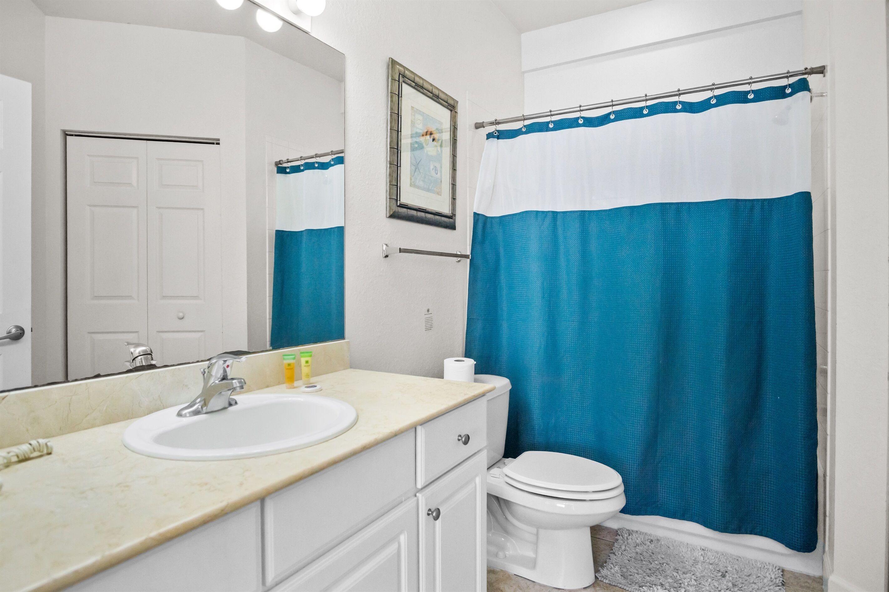 A bathroom with a white sink, mirror, and toilet.