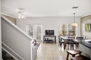 Une cuisine moderne avec un coin repas, un téléviseur et un ventilateur de plafond.
