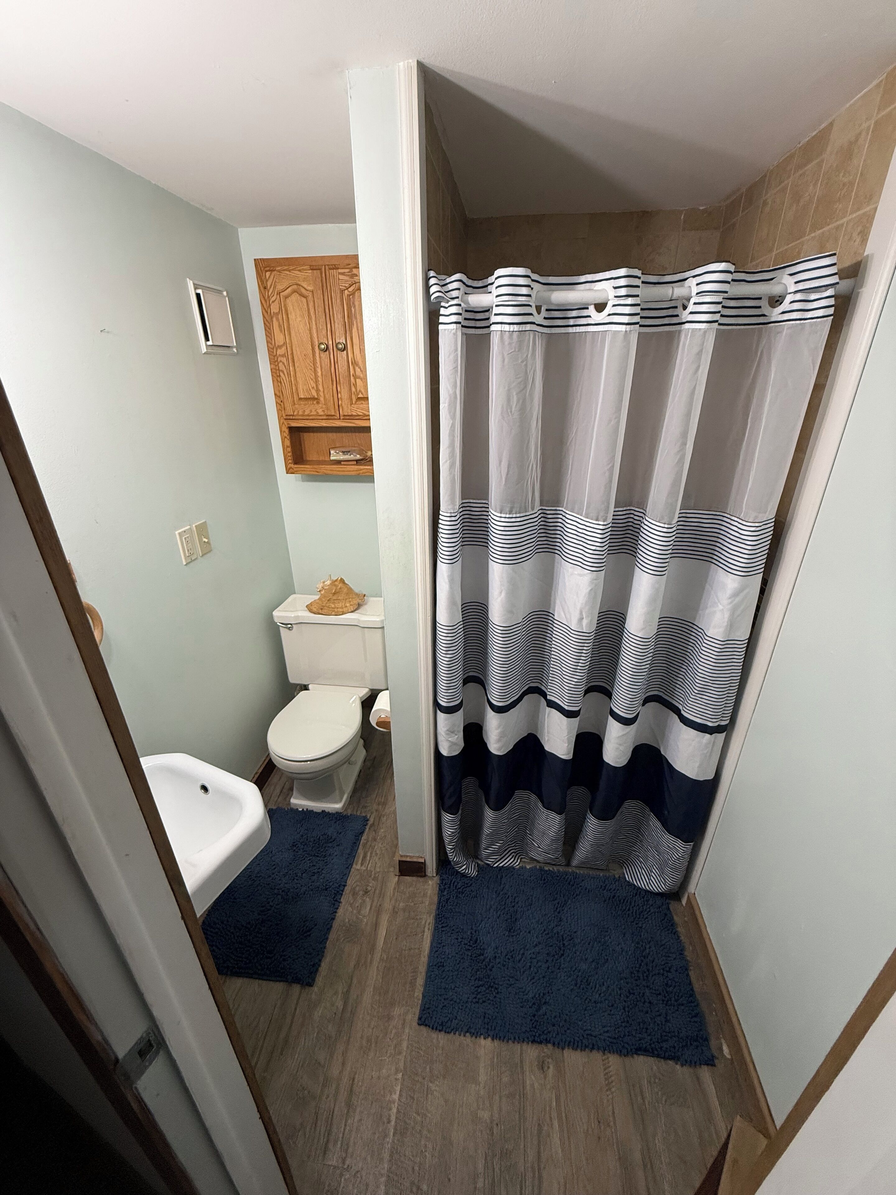 A compact bathroom with a toilet, bidet, and a shower curtain with a striped pattern.