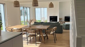 Een moderne keuken met een eethoek, houten vloeren en grote ramen.