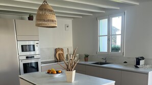 Een moderne keuken met een centraal eiland, ingebouwde apparatuur en een groot raam voor natuurlijk licht.