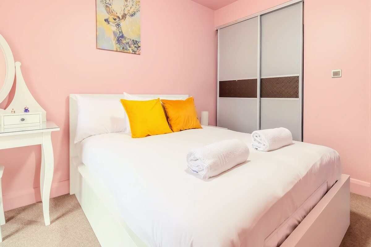 A bedroom with a bed, a nightstand, a mirror, and a sliding door.