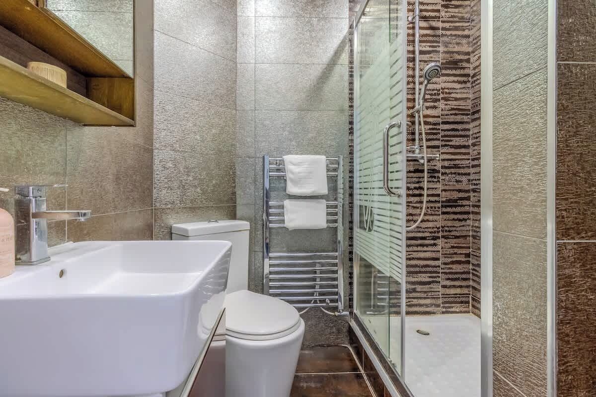 A bathroom with a sink, toilet, and glass-enclosed shower.