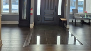 Eine moderne Lobby mit dunklem Holzboden, einer großen Bogenöffnung und einer Uhr an der Wand.